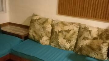 Una habitación con un sofá, una mesita de madera y una ventana con persianas.