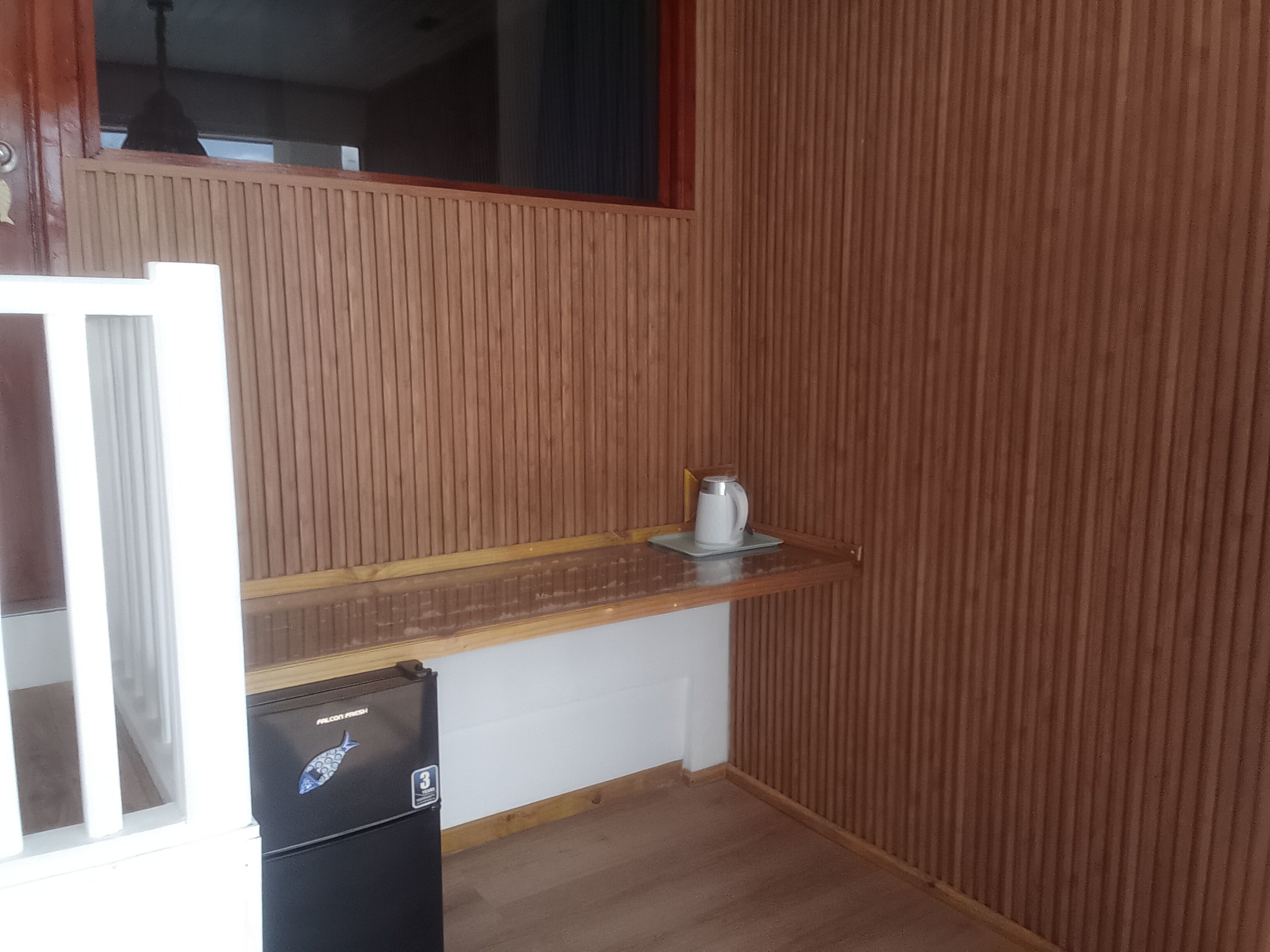A small kitchen with a wooden countertop, a coffee maker, and a refrigerator.