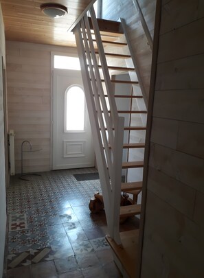 A staircase leading to a second floor, a door with a window, and a tiled floor with a geometric pattern.