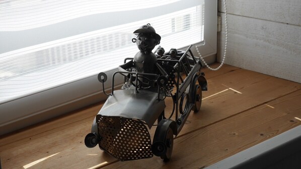 A model train on a wooden surface near a window with blinds.