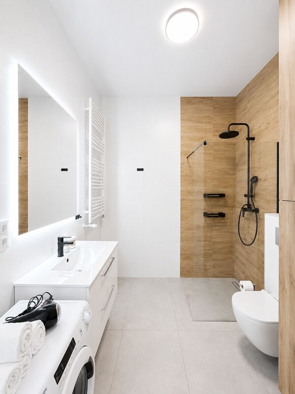 A modern bathroom with a white vanity, a built-in shower, and a toilet. - Lumina Apart neat ZOO in Lodz Parking (Łódź)