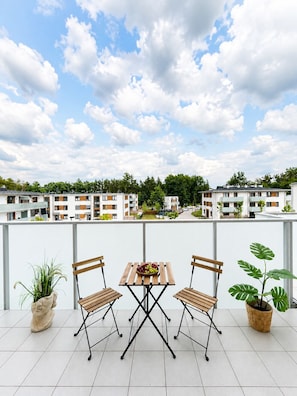 A balcony with a table and chairs, overlooking a residential area with apartment buildings. - Lumina Apart neat ZOO in Lodz Parking (Łódź)