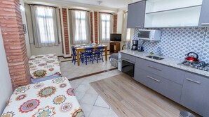 A compact kitchen with a dining area, a microwave, a gas stove, and a television. - Direita S.Antonio-Comfort Street Quarto e sala para 5 pessoas, vista c.historico. (Salvador)