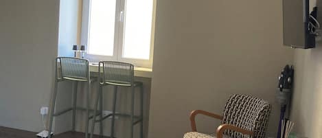 Ein Wohnzimmer mit Essbereich, einer Topfpflanze und einem an der Wand befestigten Fernseher.