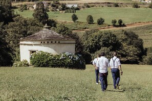 A rural landscape with a small white building, a grassy field, and trees. - Pazo de Cedofeita (Ribadeo). Historical house of the XVI century, with private property. (Ribadeo)