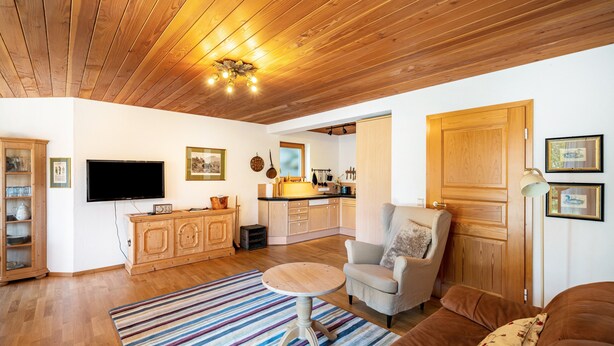 A living room with a wooden ceiling, a television, a kitchen in the background, a dining area, and a sofa. - Apartment "Time Out in the Black Forest" with Private Terrace, Garden & Wi-Fi (Schonach im Schwarzwald)