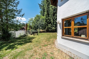 A residential property with a fenced yard, a wooden bench, and a large window.