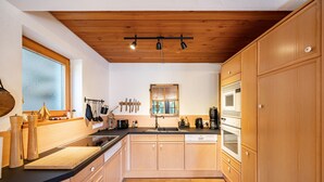 A modern kitchen with wooden cabinets, a black countertop, and a wooden ceiling. - Apartment "Time Out in the Black Forest" with Private Terrace, Garden & Wi-Fi (Schonach im Schwarzwald)