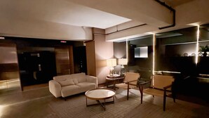 Ein modernes Wohnzimmer mit einer Couch, einem runden Couchtisch und einem Sessel. An der Wand ist ein Flachbildfernseher angebracht.