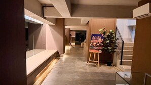 Ein Flur mit einer Rezeption, einer Treppe und einem Plakat.