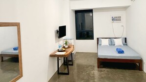 Ein kleiner, moderner Raum mit Bett, Schreibtisch, Fernseher und Fenster.