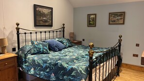 Ein Schlafzimmer mit einem Bett, einem Nachttisch, einer Lampe und zwei gerahmten Bildern an der Wand.
