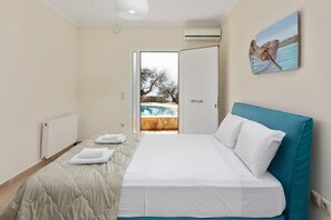 Ein Schlafzimmer mit Bett, Blick auf einen Außenpool und einer Tür zum Ausgang.