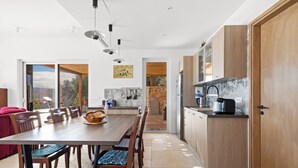 Una cocina moderna con armarios de madera, un comedor con mesa y sillas, y una pared de piedra.