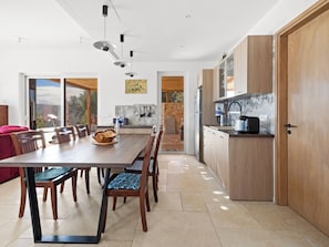 Eine moderne Küche mit Holzausstattung, einem Essbereich mit Tisch und Stühlen sowie einer Steinwand.