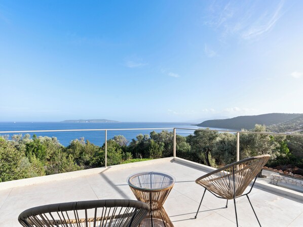 A terrace with two wicker chairs and a glass table, overlooking a beach and the sea. - Villa Thymari, new cocoon of privacy and peace (sivota village)