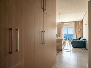 Ein modernes Hotelzimmer mit großem Kleiderschrank, einer Essecke mit Aussicht und einem Balkon mit Tisch und Stühlen.