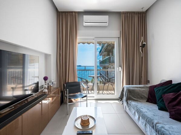Une chambre d’hôtel moderne dotée d’un balcon, d’une télévision à écran plat, d’un coin repas et d’un canapé.