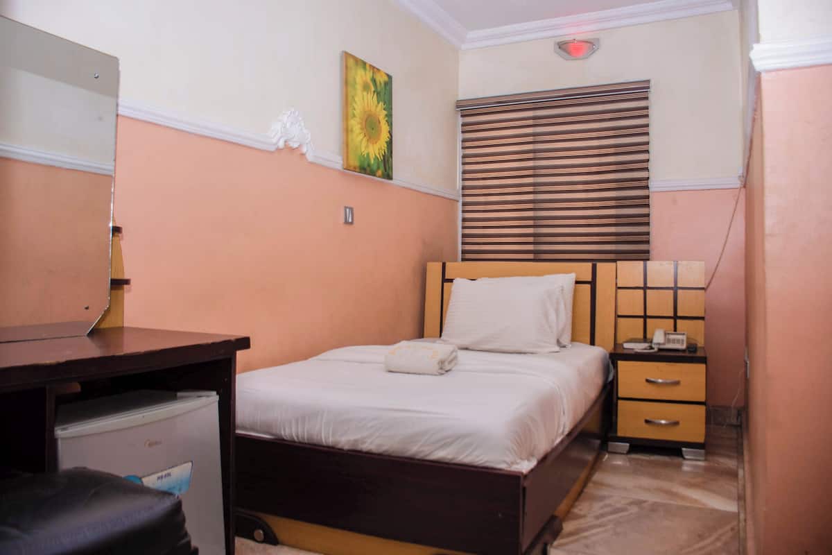 A bedroom with a bed, bedside table, and a small desk with a chair.