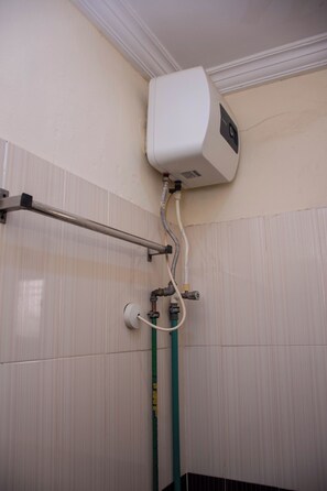 Une salle de bain avec des toilettes blanches, un sèche-mains et un porte-serviettes.
