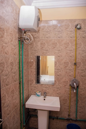 Un baño con lavamanos blanco, un espejo y un dispensador de papel higiénico.