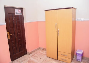 Una habitación con puerta de madera, un armario, un cubo de basura y un cartel de 'No Fumar'.