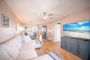 Ein Wohnzimmer mit Sofa, Fernseher und Blick auf den Strand.