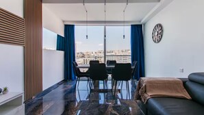 Una sala de estar moderna con comedor, ventanas amplias y vista a la ciudad.