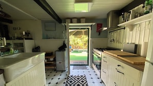 Een keuken met een patroon vloer, een koelkast, een fornuis en een raam met uitzicht op een tuin.
