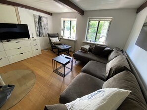 A living room with a sofa, a coffee table, a TV, and a chair.