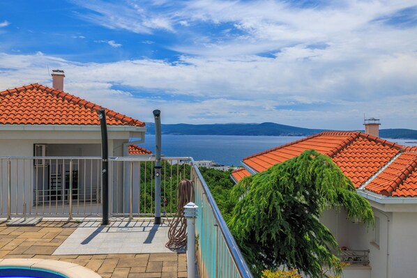 Ein Wohngebäude mit Ziegeldach, einem Balkon und Blick auf das Meer.