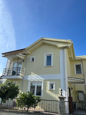 Un bĂątiment Ă deux Ă©tages dotĂ© dâun balcon, de fenĂȘtres et surplombant un ciel dĂ©gagĂ©.
