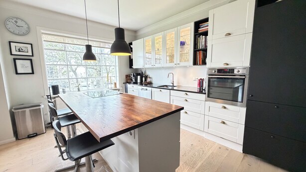 A modern kitchen with a central island, pendant lighting, and a stainless steel refrigerator. - Stylish apartment in the heart of Reykjavík, Vesturbær (Reykjavík)