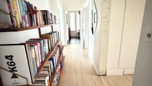A hallway with bookshelves on both sides, a wooden floor, and a door at the end. - Stylish apartment in the heart of Reykjavík, Vesturbær (Reykjavík)