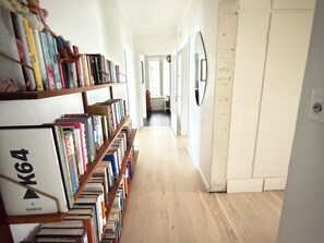Ein Korridor mit Bücherregalen an beiden Seiten, Holzboden und einer Tür am Ende.