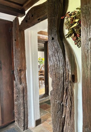 Marco de puerta de madera rústico con un letrero, un poste de madera con un arreglo floral, y vista a un cuarto con una mesa y sillas de comedor.