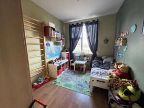 Ein Kinderzimmer mit Bett, Schreibtisch, Regalen und einem Fenster.