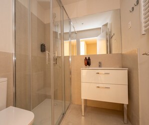 A modern bathroom with a glass-enclosed shower, a white vanity with drawers, and a mirror above the sink. - Be Mate Chamberí - Temporary Stays (Madrid)