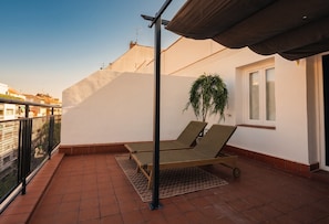 A balcony with two lounge chairs, a potted plant, and a window. - Be Mate Chamberí - Temporary Stays (Madrid)