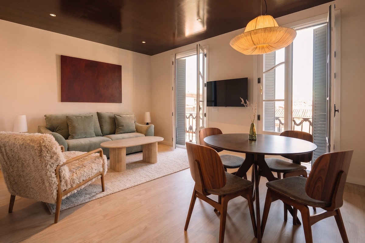 A modern living room with a sofa, coffee table, and dining area with chairs.