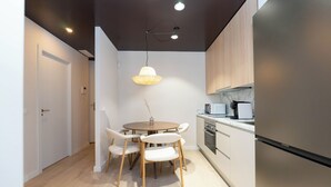A modern kitchen with a round dining table, white chairs, a hanging pendant light, and built-in appliances. - Be Mate Chamberí - Temporary Stays (Madrid)