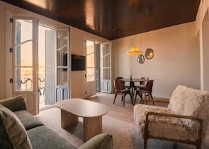 An open-plan living space with a dining area, sofas, a coffee table, and a television mounted on the wall. - Be Mate Chamberí - Temporary Stays (Madrid)