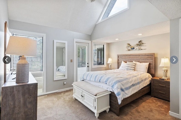 Ein Schlafzimmer mit einem Bett, Nachttischen, einer Bank, einer Lampe und einem Dachfenster.