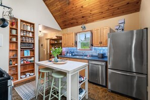 A kitchen with wooden cabinets, a stainless steel refrigerator, and a window providing natural light.