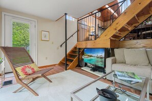 A living room with a wooden staircase, a sofa, a TV, and a book on a coffee table.