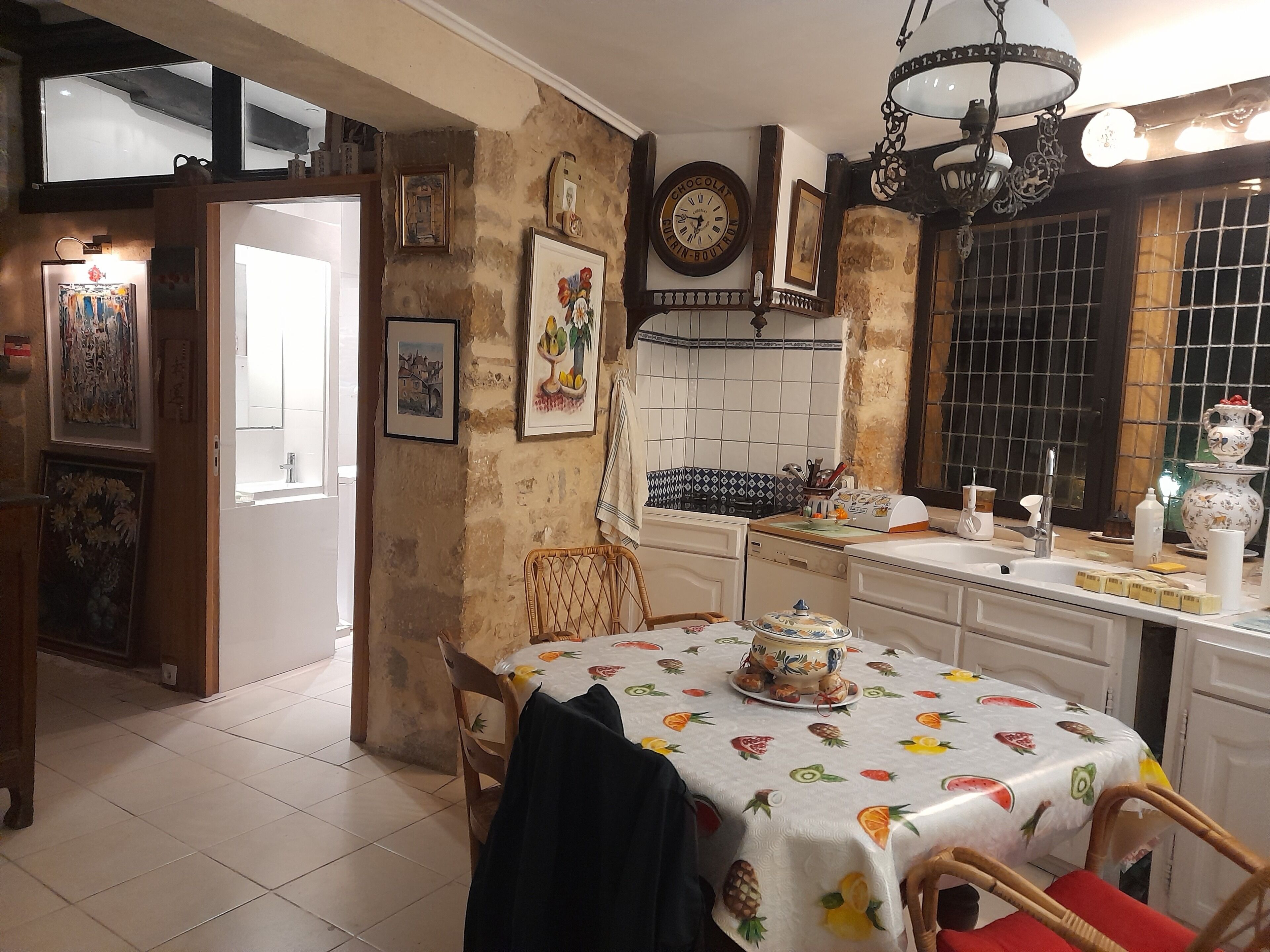 A kitchen with a dining table, chairs, a clock, and various kitchen items.
