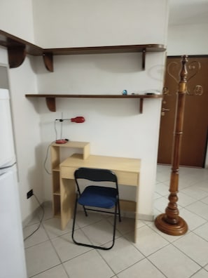 A room with a desk, chair, shelves, and a floor lamp. - De Blasi Studio Apartment (Lecce)