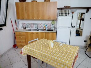 Eine kleine Küche mit Holzschränken, einem Spülbecken und einem Kühlschrank.