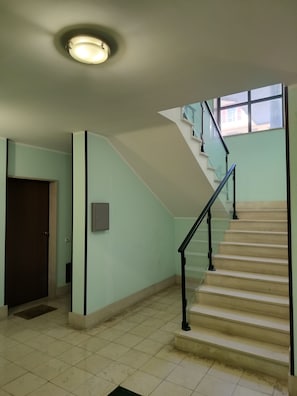 Eine Treppe mit Handlauf, einer Tür und einer Deckenleuchte.