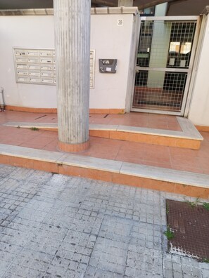Ein Gebäudeeingang mit Fliesenboden, einem Metallgitter und einer Säule.